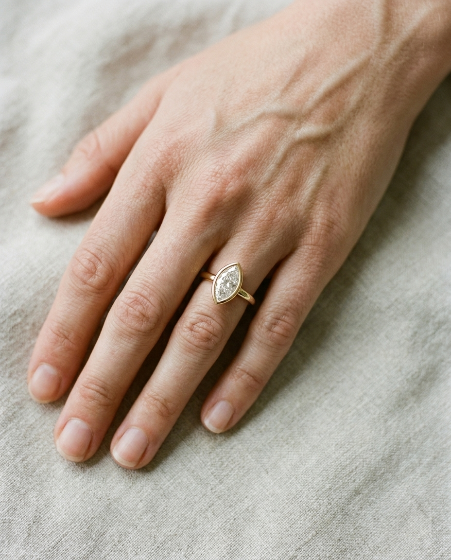 The Agnes Select bezel solitaire marquise engagement ring in 18k yellow gold — top down hand — RockHer