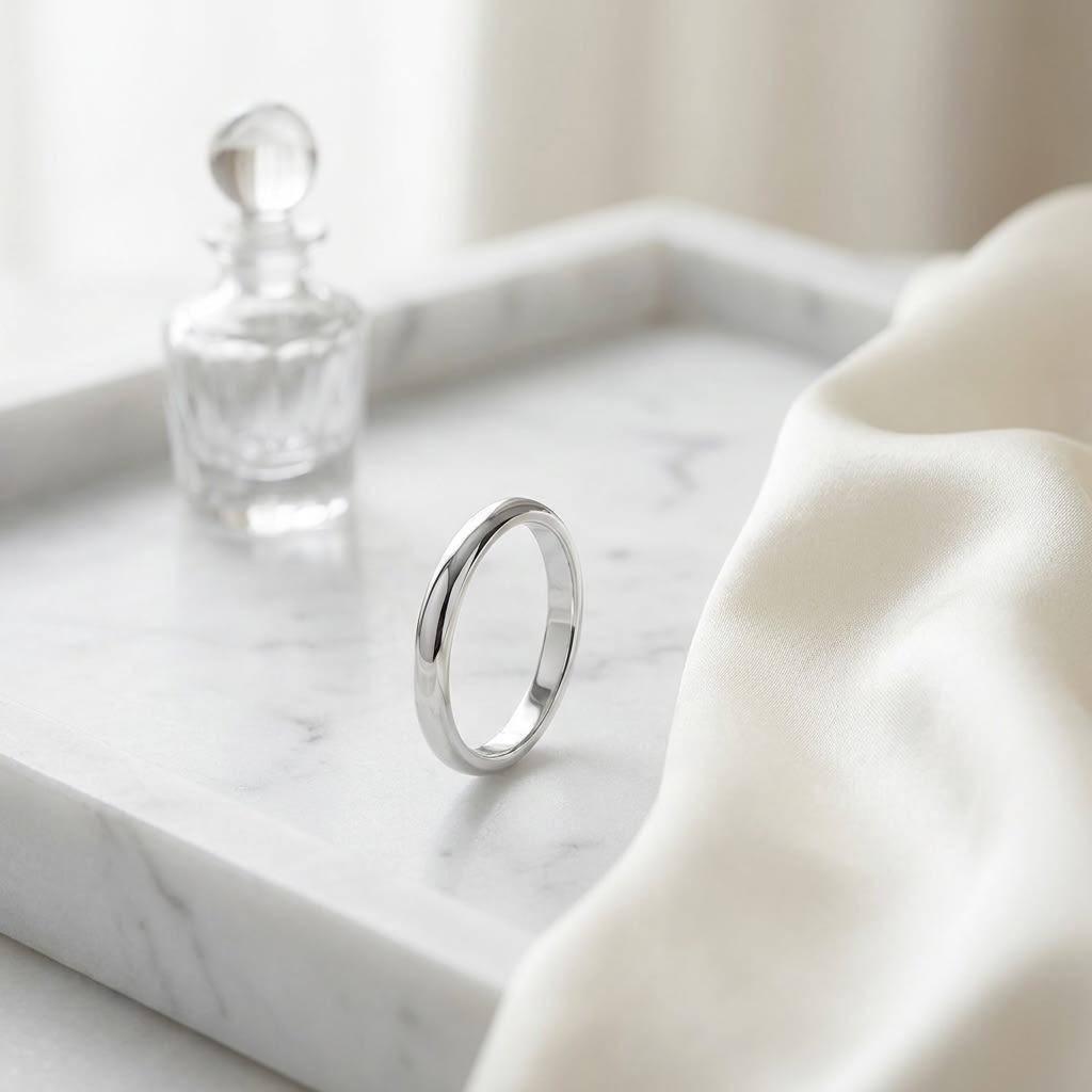 2mm Slightly Domed Traditional Oval Wedding Band in 18K White Gold, on marble vanity tray with silk