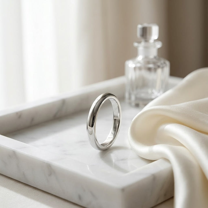 2.5mm Slightly Domed Traditional Oval Wedding Band in 18K White Gold, on marble vanity tray with silk