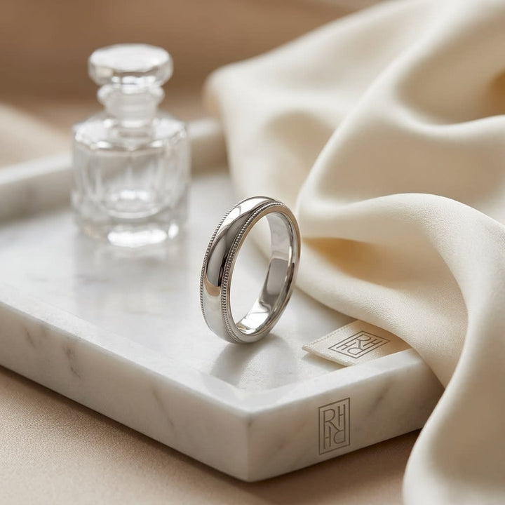 4mm Slightly Domed Traditional Oval Milgrain Wedding Band in 18K White Gold, on marble vanity tray with silk