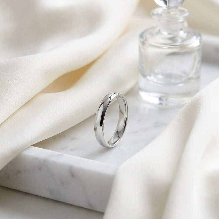 4mm Slightly Domed Comfort-Fit Wedding Band in 18K White Gold, on marble vanity tray with silk