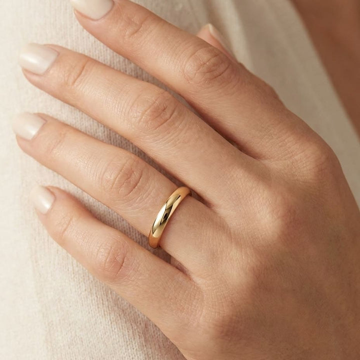 2mm Slightly Domed Traditional Oval Wedding Band in 18K Yellow Gold, worn on hand, close-up