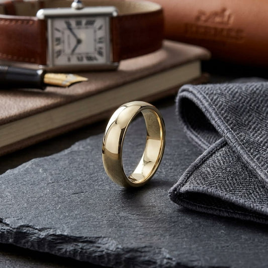 5mm Slightly Domed Traditional Oval Wedding Band in 18K Yellow Gold, on walnut surface with pocket square