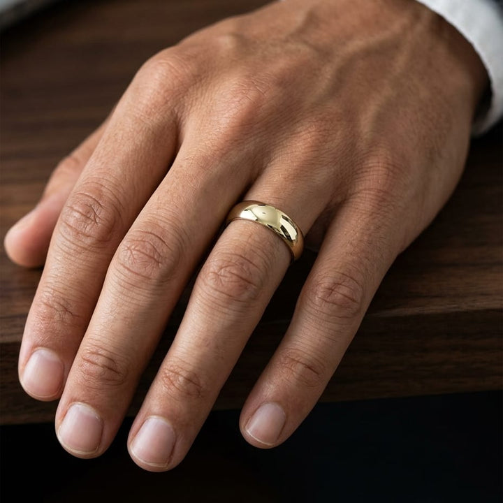 6mm Slightly Domed Traditional Oval Wedding Band in 18K Yellow Gold, worn on hand, masculine close-up