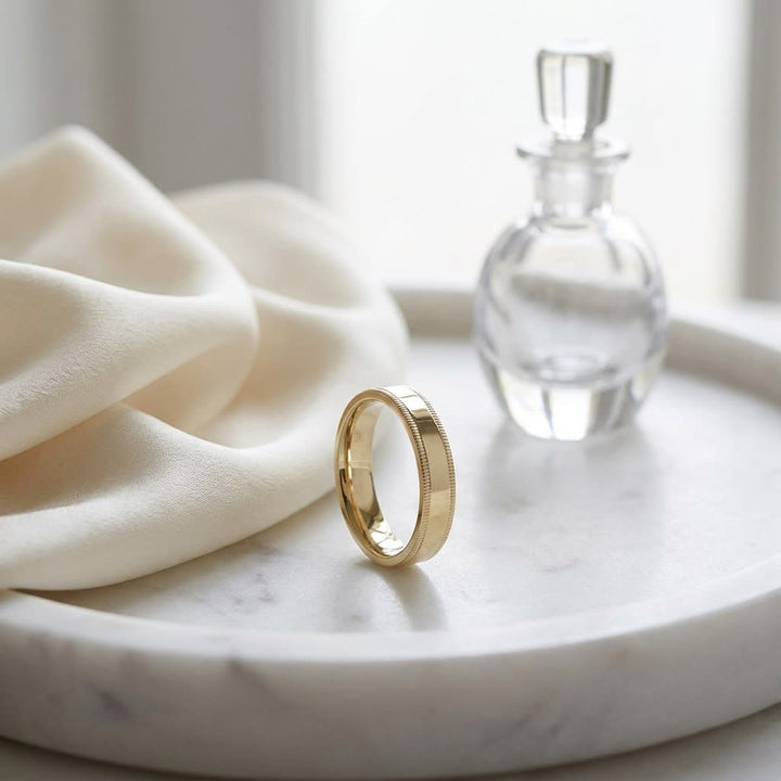 4mm Flat Milgrain Comfort-Fit Wedding Band in 18K Yellow Gold, on marble vanity tray with silk