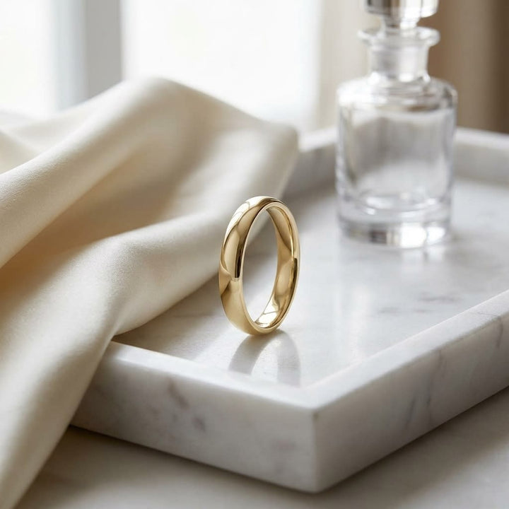 4mm Slightly Domed Comfort-Fit Wedding Band in 18K Yellow Gold, on marble vanity tray with silk