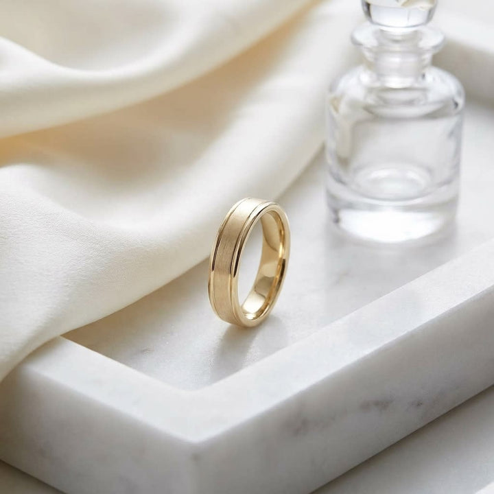 4mm Satin Finish High Polished Round Edge Carved Wedding Band in 18K Yellow Gold, on marble vanity tray with silk