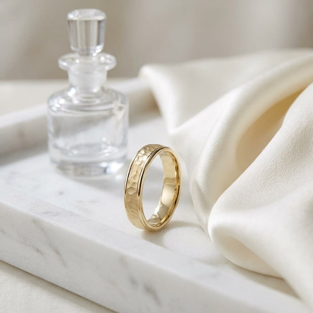 4mm Hammered Finish Carved Wedding Band in 18K Yellow Gold, on marble vanity tray with silk
