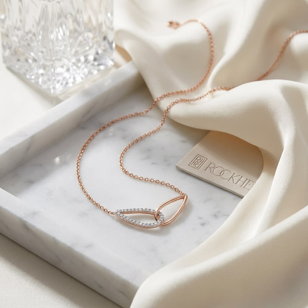 Diamond Pave And High Polish Teardrop Interlink Necklace in 14K Rose Gold, 16-18 Inch, on marble vanity tray with silk