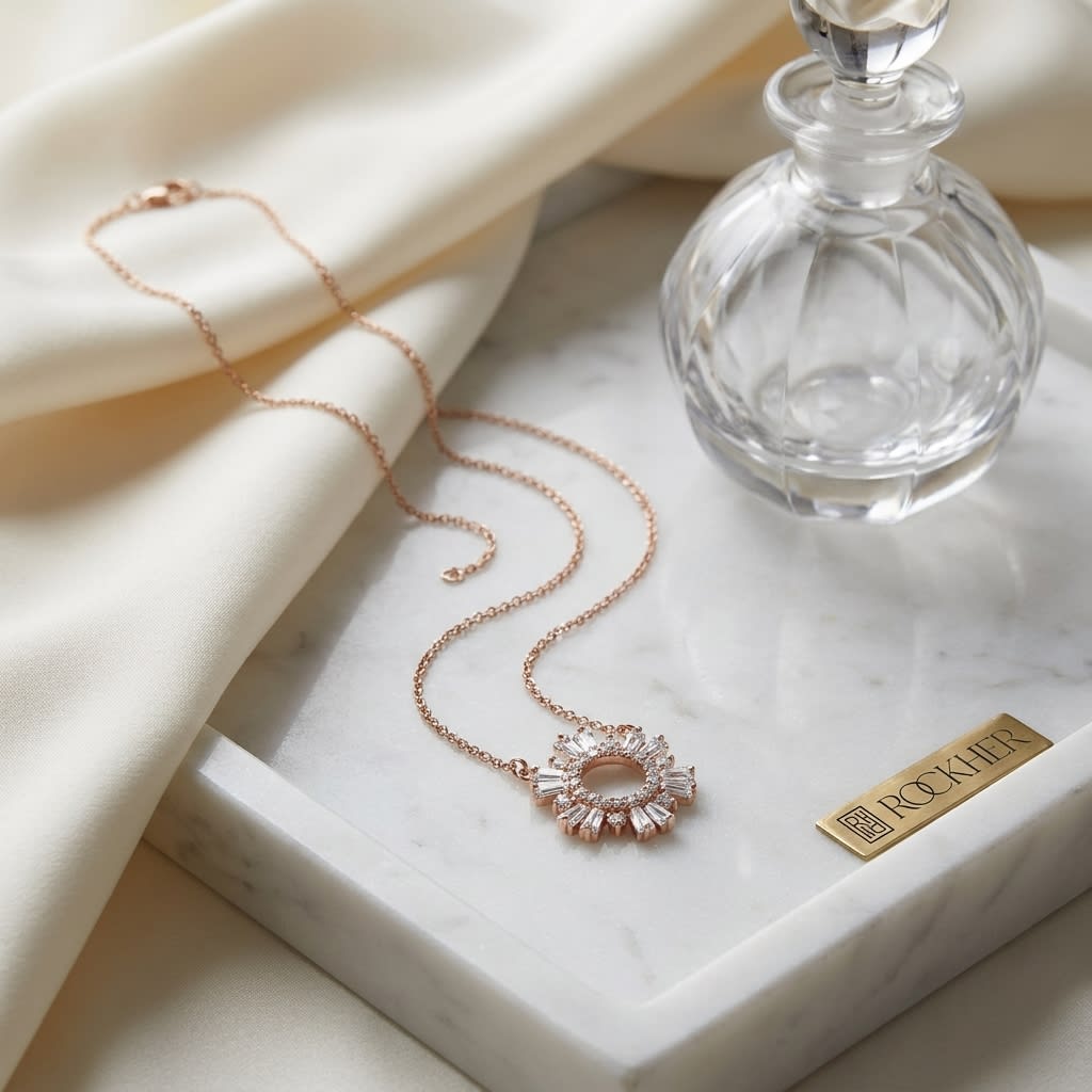 Diamond Pave Circle And Tapered Baguette Starburst Necklace in 14K Rose Gold, on marble vanity tray with silk