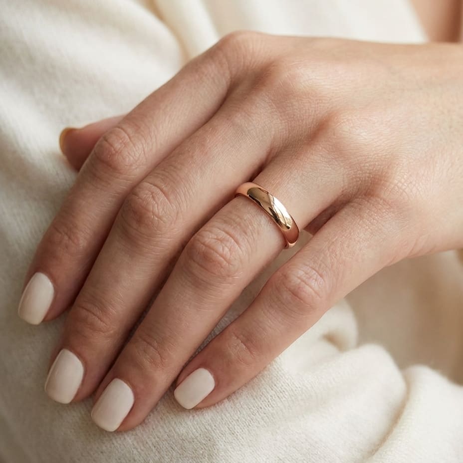 4mm Slightly Domed Traditional Oval Wedding Band in 14K Rose Gold, worn on hand, close-up