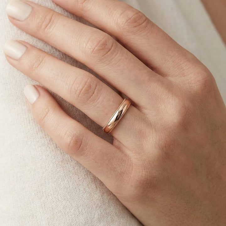 4mm Slightly Domed Traditional Oval Milgrain Wedding Band in 14K Rose Gold, worn on hand, close-up