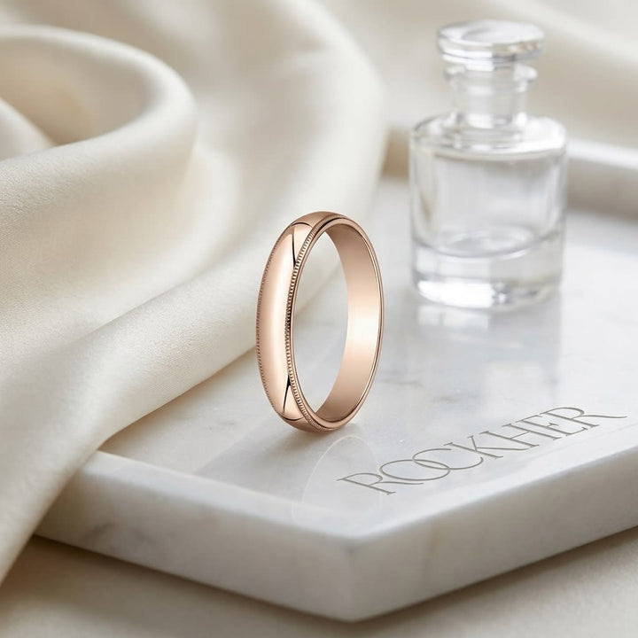 4mm Slightly Domed Traditional Oval Milgrain Wedding Band in 14K Rose Gold, on marble vanity tray with silk