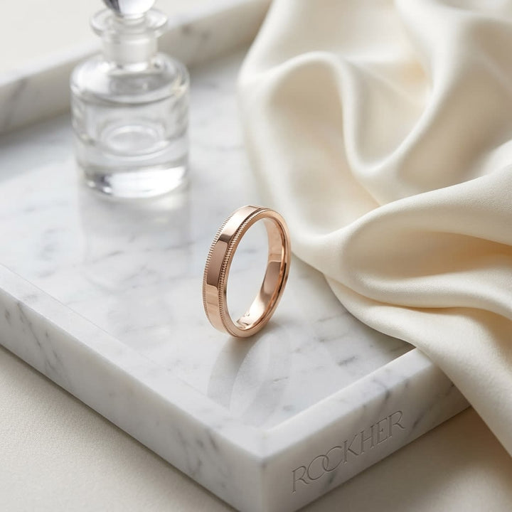 4mm Flat Milgrain Comfort-Fit Wedding Band in 14K Rose Gold, on marble vanity tray with silk