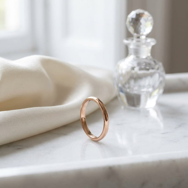 2mm Slightly Domed Comfort-Fit Wedding Band in 14K Rose Gold, on marble vanity tray with silk