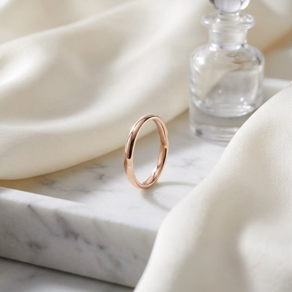 2.5mm Slightly Domed Comfort-Fit Wedding Band in 14K Rose Gold, on marble vanity tray with silk