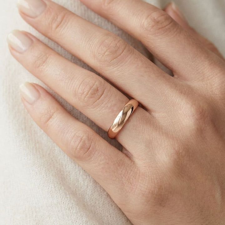 4mm Slightly Domed Comfort-Fit Wedding Band in 14K Rose Gold, worn on hand, close-up