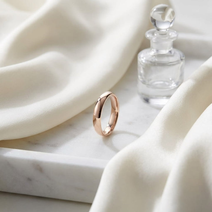 4mm Slightly Domed Comfort-Fit Wedding Band in 14K Rose Gold, on marble vanity tray with silk