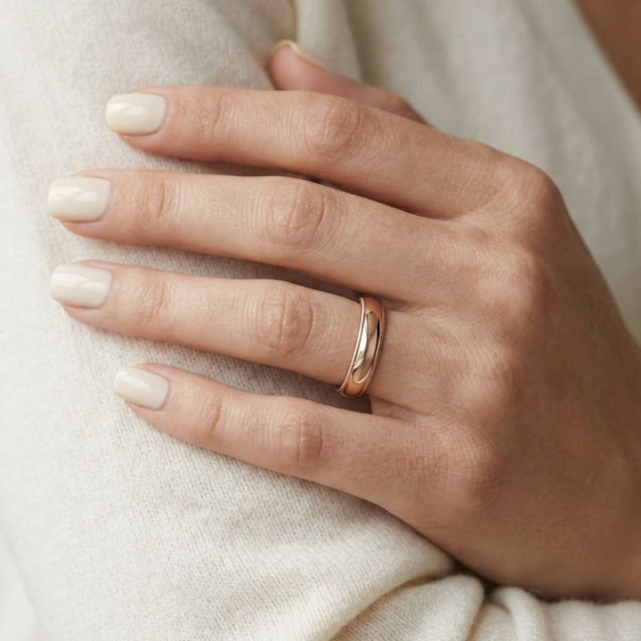 4mm Slightly Domed Milgrain Comfort-Fit Wedding Band in 14K Rose Gold, worn on hand, close-up
