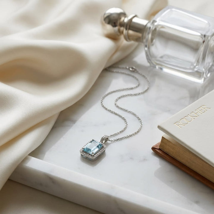 Aquamarine Emerald Cut Halo Pendant in 14k White Gold 0.15ctw, on marble vanity tray with silk