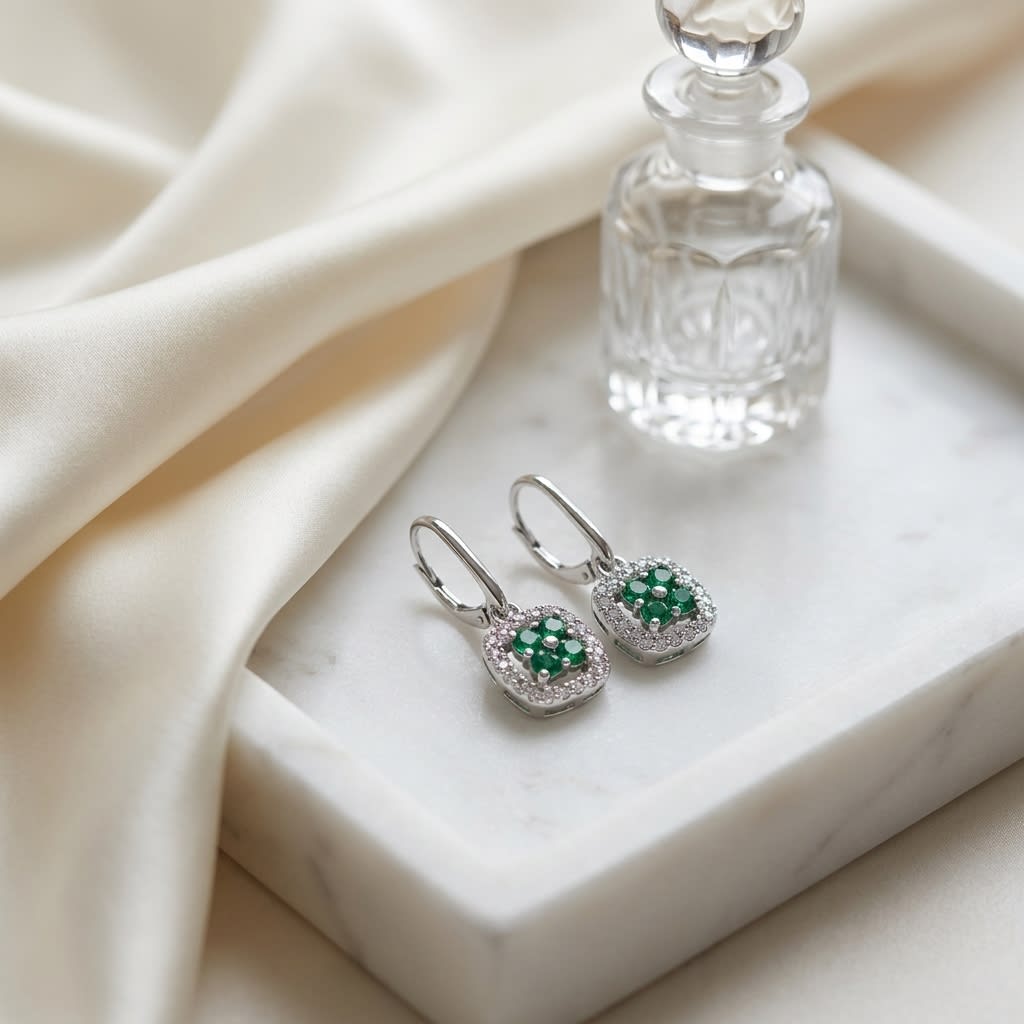 Created Emerald And Diamond Dangle Clover Leverback Earrings in 14K White Gold, on marble vanity tray with silk