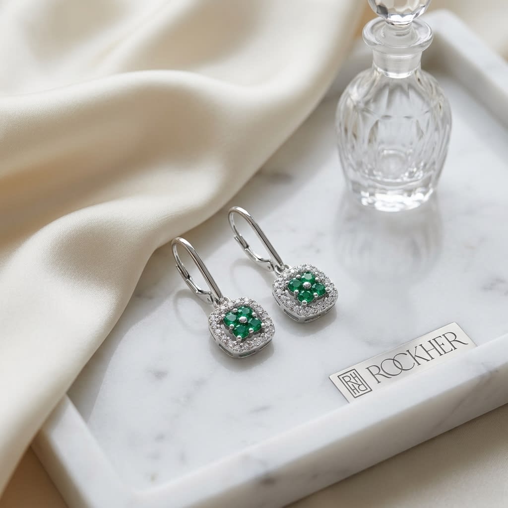 Created Emerald And Diamond Dangle Clover Leverback Earrings in 14K White Gold, on marble vanity tray with silk