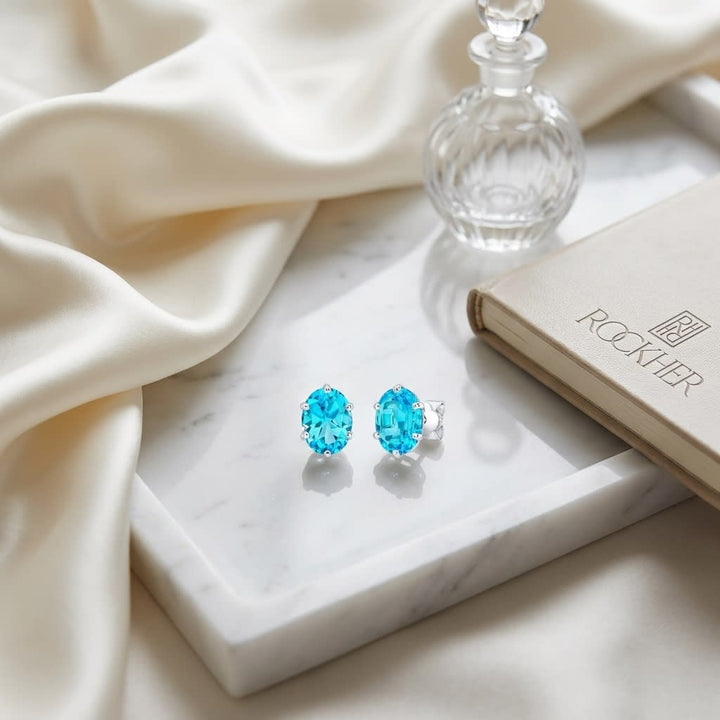 Swiss Blue Topaz Oval Stud Earrings in 14K White Gold, on marble vanity tray with silk