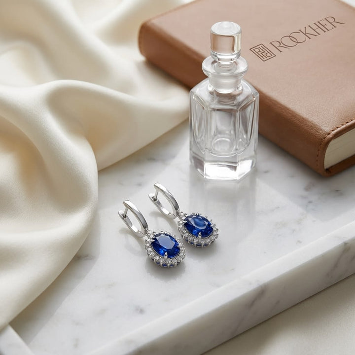 Sapphire Oval And Diamond Starburst Frame Earrings in 14K White Gold, on marble vanity tray with silk