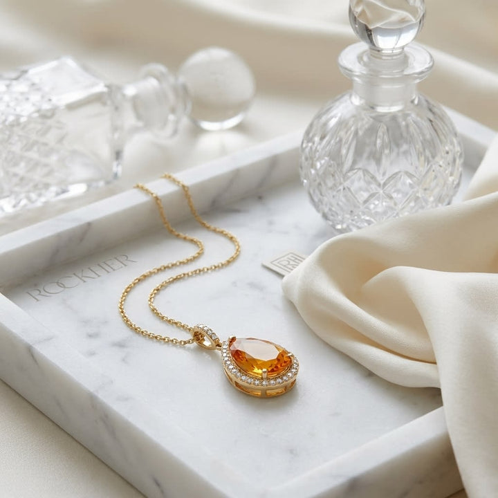 Citrine Pear Shape Halo Pendant in 14K Yellow Gold, on marble vanity tray with silk