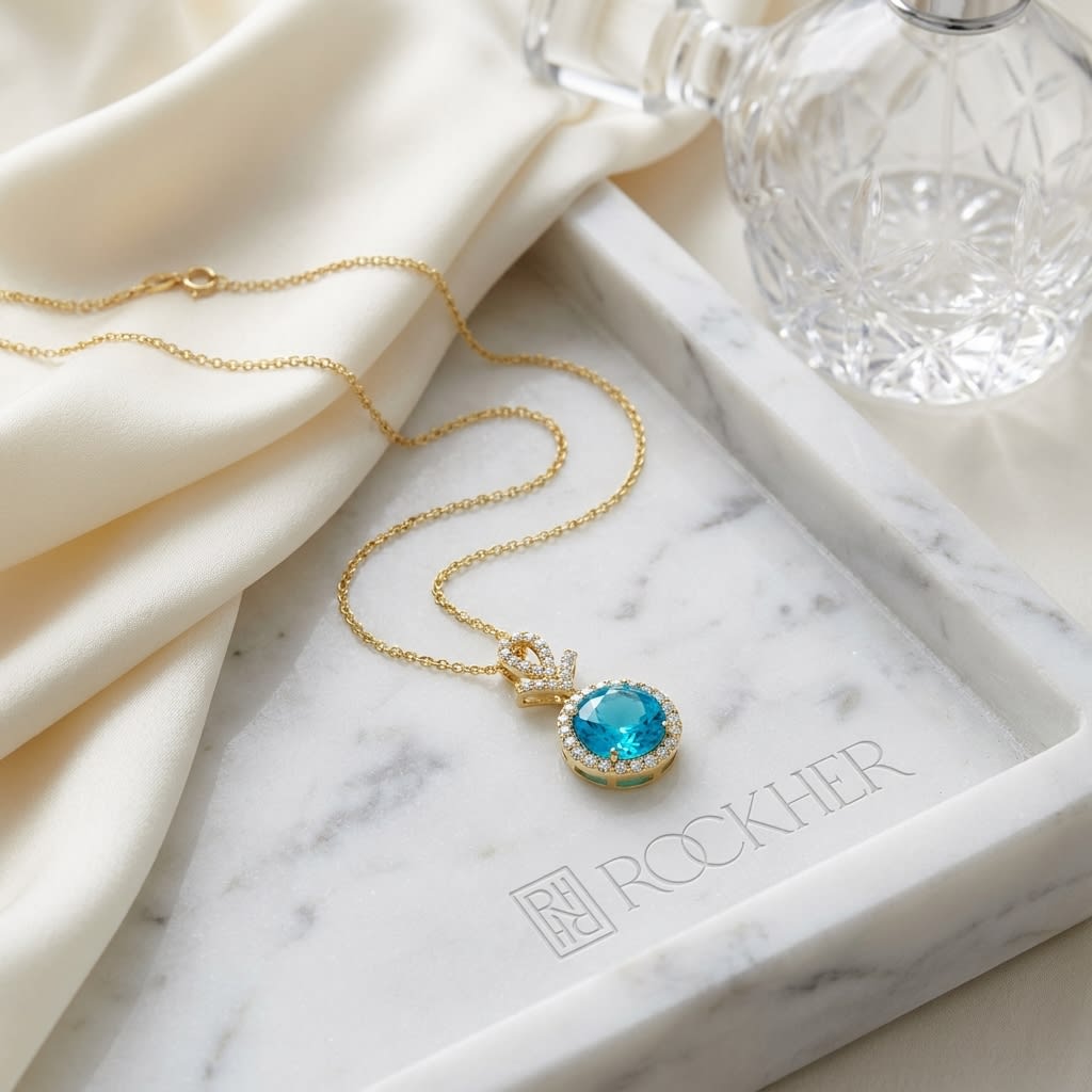 Swiss Blue Topaz Halo Pendant in 14K Yellow Gold, on marble vanity tray with silk