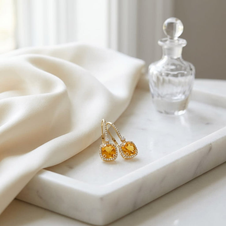 Citrine And Diamond Halo Cushion Dangle Earrings in 14K Yellow Gold 0.28ctw, on marble vanity tray with silk