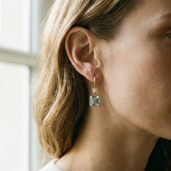 Swiss Blue Topaz Bezel Earrings in 14k Yellow Gold 0.08ctw, worn close-up portrait