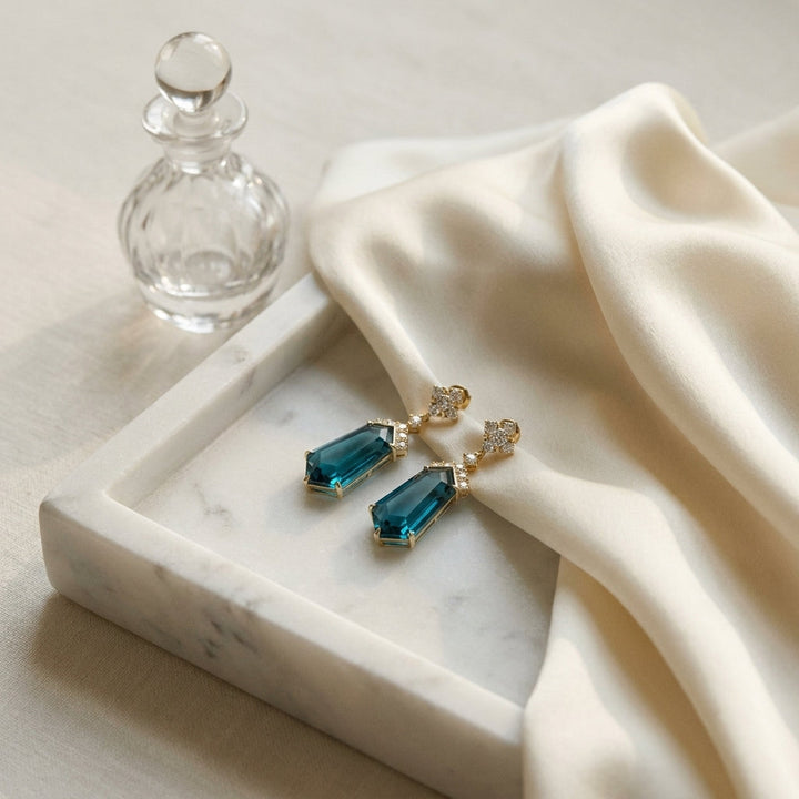 London Blue Topaz and Diamond Shield Drop Earrings in 14k Yellow Gold 0.27ctw, on marble vanity tray with silk