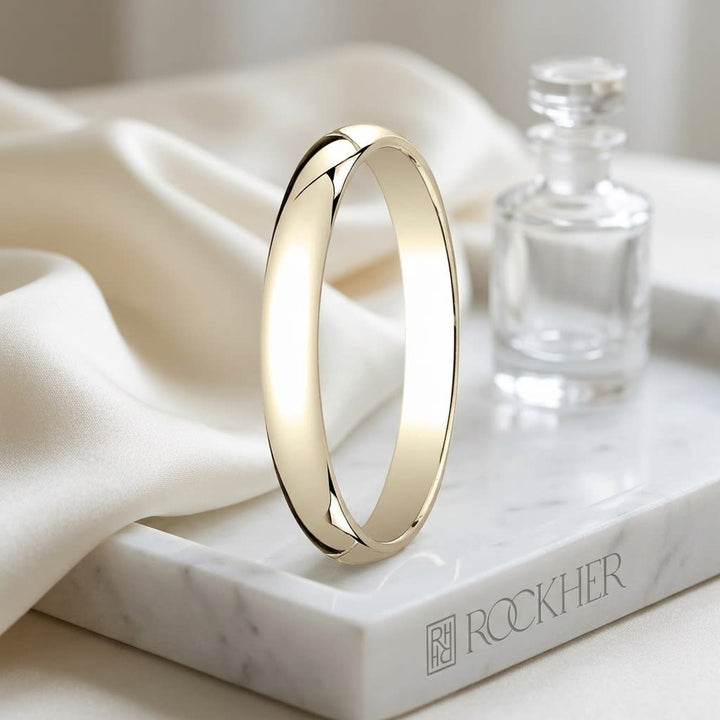 3mm Slightly Domed Traditional Oval Wedding Band in 14K Yellow Gold, on marble vanity tray with silk