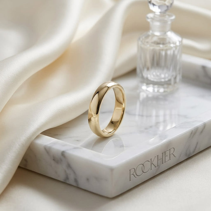 4mm Slightly Domed Traditional Oval Wedding Band in 14K Yellow Gold, on marble vanity tray with silk