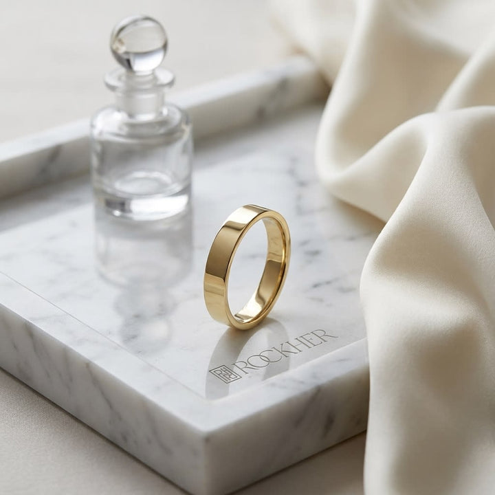 4mm Traditional Flat Wedding Band in 14K Yellow Gold, on marble vanity tray with silk