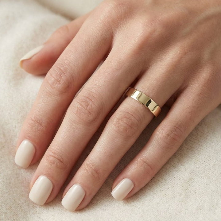 4mm Flat Comfort-Fit Wedding Band in 14K Yellow Gold, worn on hand, close-up