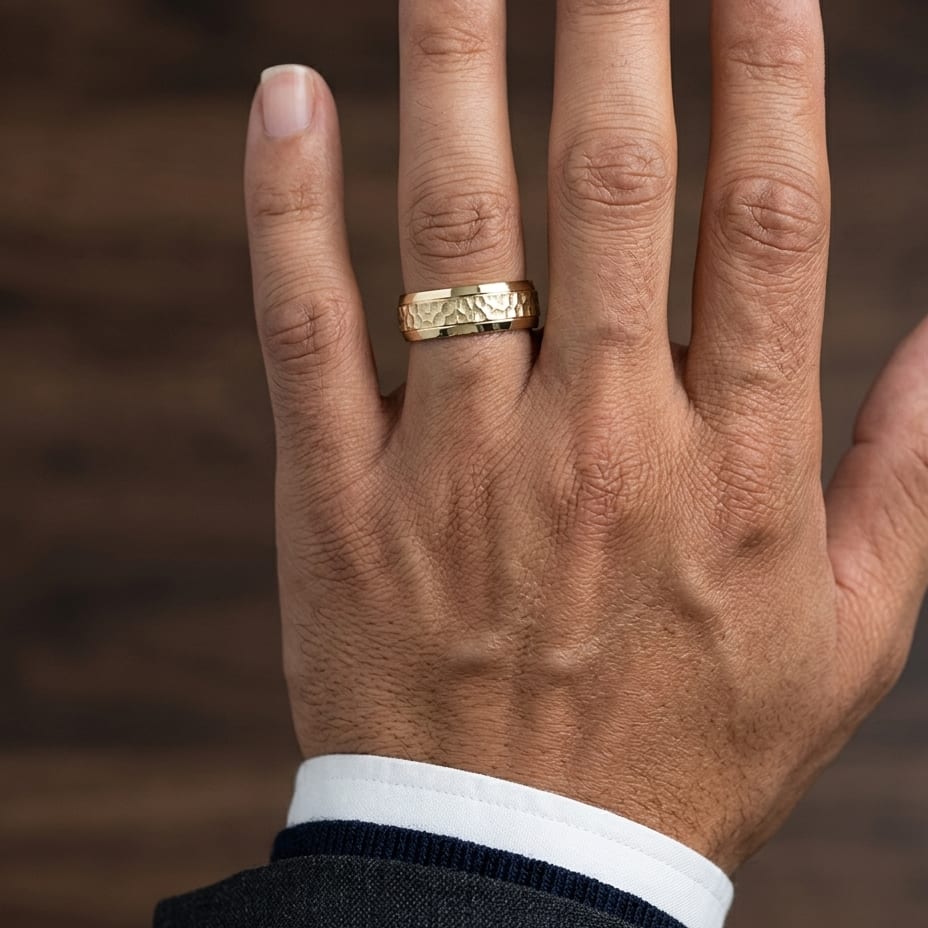 7.5mm Hammered Finish Beveled Edge Carved Wedding Band in 14K Yellow Gold, worn on hand, masculine close-up