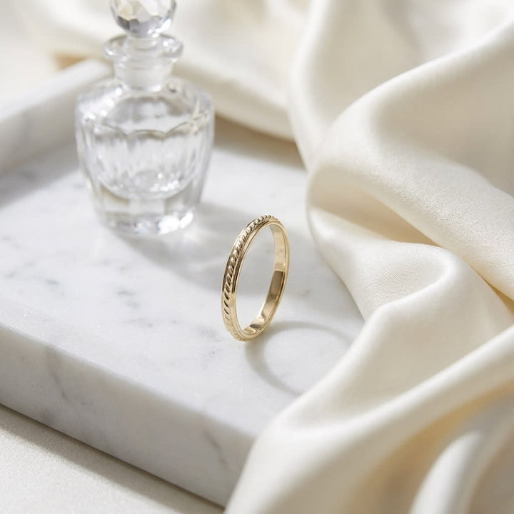 2mm High Polish Carved Wedding Band in 14K Yellow Gold, on marble vanity tray with silk
