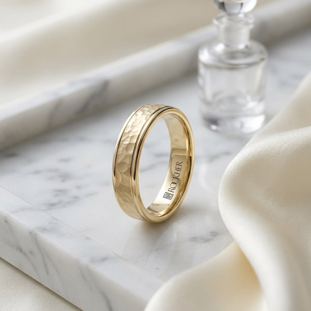 4mm Hammered Finish Carved Wedding Band in 14K Yellow Gold, on marble vanity tray with silk