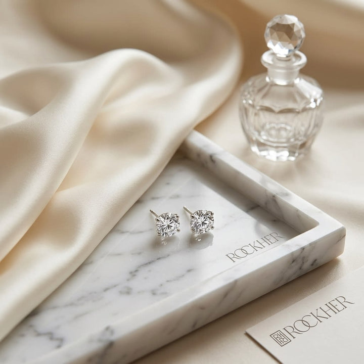 Natural Diamond Round Brilliant Three Prong Martini Stud Earrings in Platinum, 1 ct. t.w., on marble vanity tray with silk