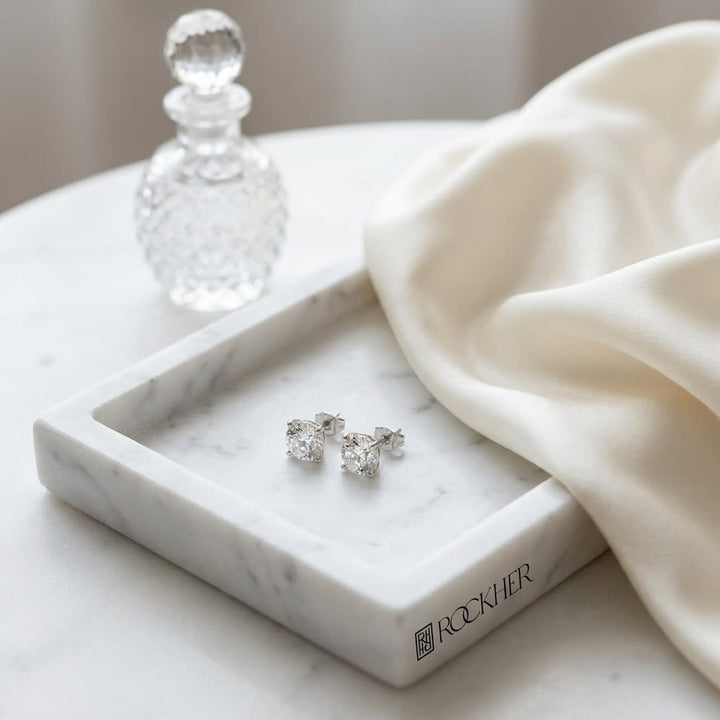 Natural Diamond Round Brilliant Four Prong Stud Earrings in Platinum, 1-1/2 ct. t.w., on marble vanity tray with silk