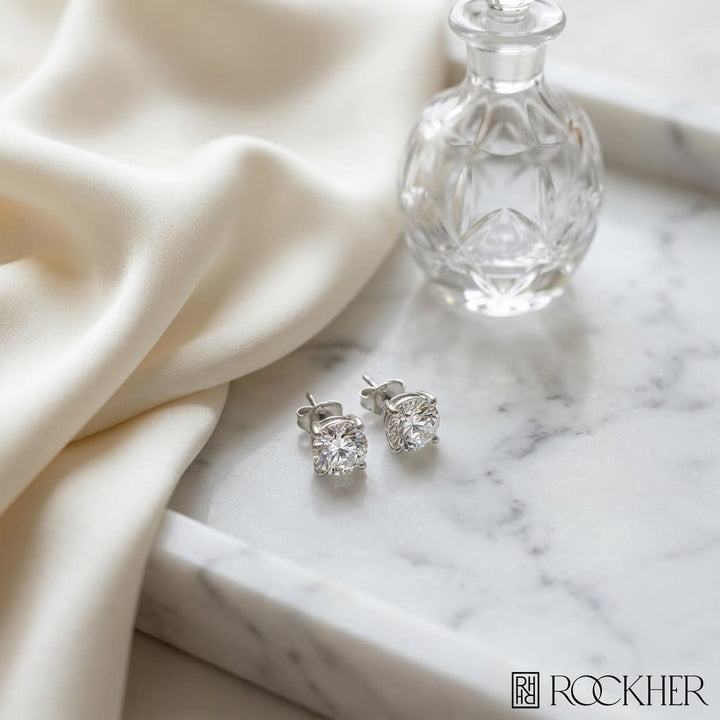 Platinum 4-prong Round Brilliant Diamond Stud Earrings (2.09 Ct. T.w., Vs1-vs2 Clarity, H-i Color), on marble vanity tray with silk