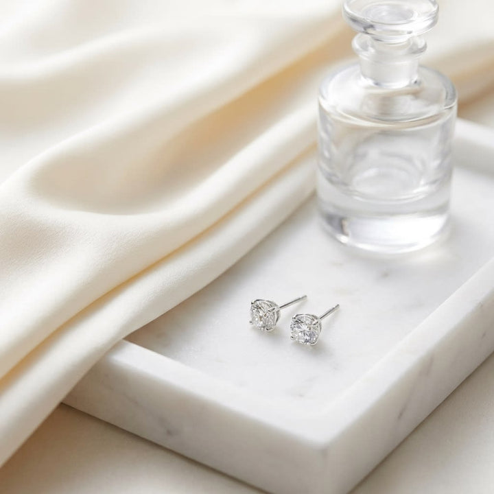Natural Diamond Round Brilliant Bezel Stud Earrings in Platinum, 2 ct. t.w., on marble vanity tray with silk