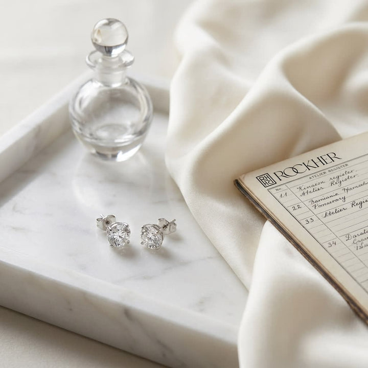 Platinum Bezel Set Round Brilliant Diamond Stud Earrings (1 Ct. T.w., Si1-si2 Clarity, J-k Color), on marble vanity tray with silk
