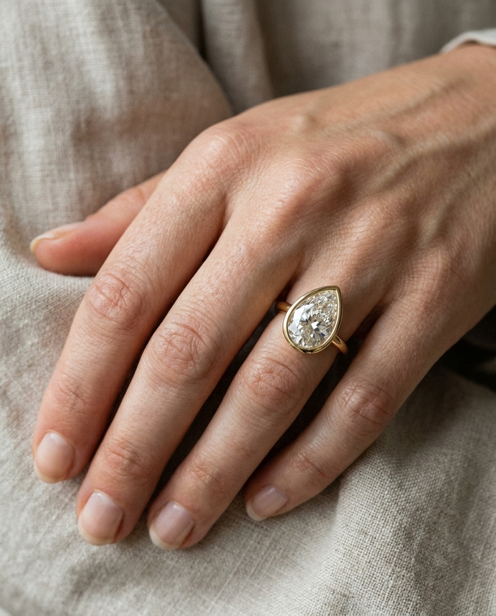 The Agnes Select bezel solitaire briolette engagement ring in 18k yellow gold — on hand — RockHer