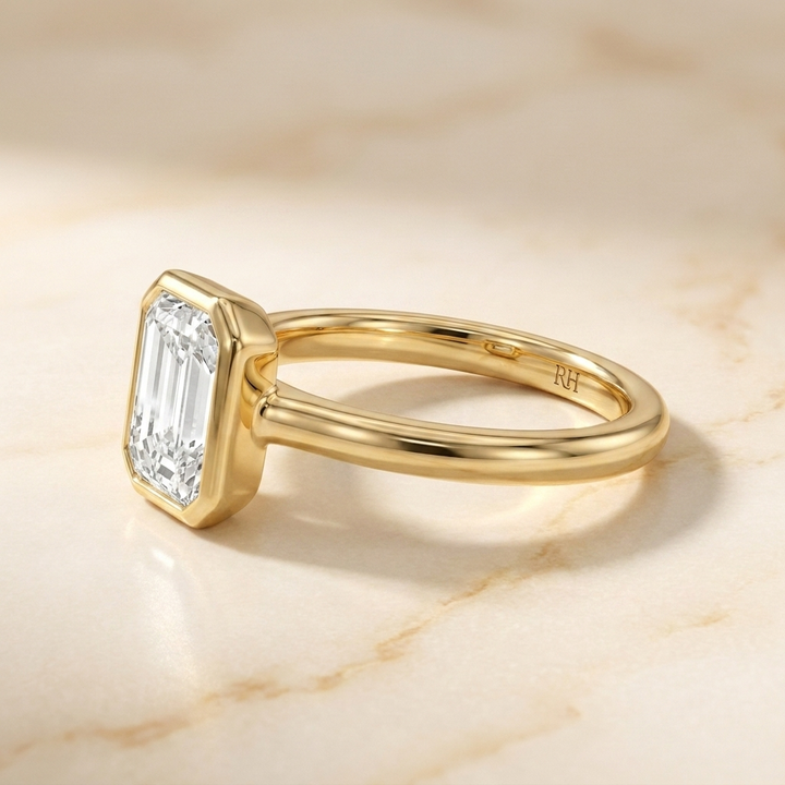 The Agnes Select bezel solitaire emerald cut engagement ring in 18k yellow gold — side profile — RockHer