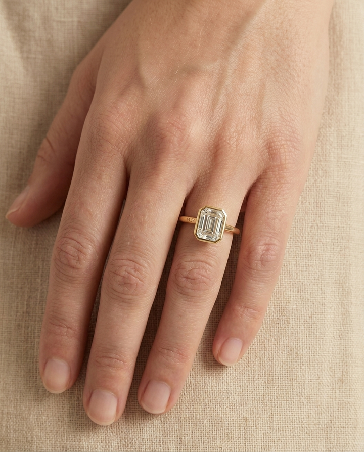 The Agnes Select bezel solitaire emerald cut engagement ring in 18k yellow gold — top down hand — RockHer