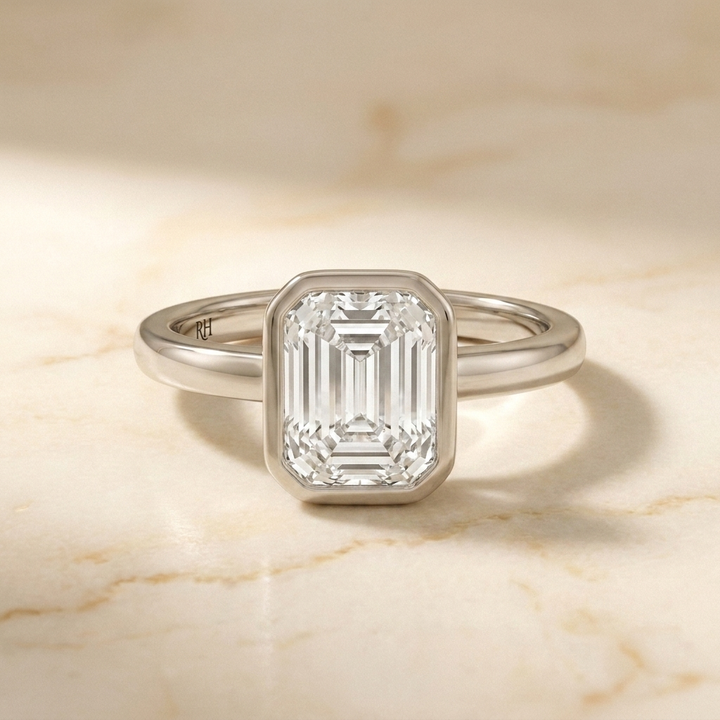 The Agnes Select bezel solitaire emerald cut engagement ring in 18k white gold — front view — RockHer