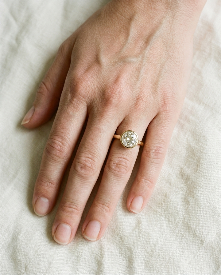 The Agnes Select bezel solitaire old european cut engagement ring in 18k yellow gold — top down hand — RockHer